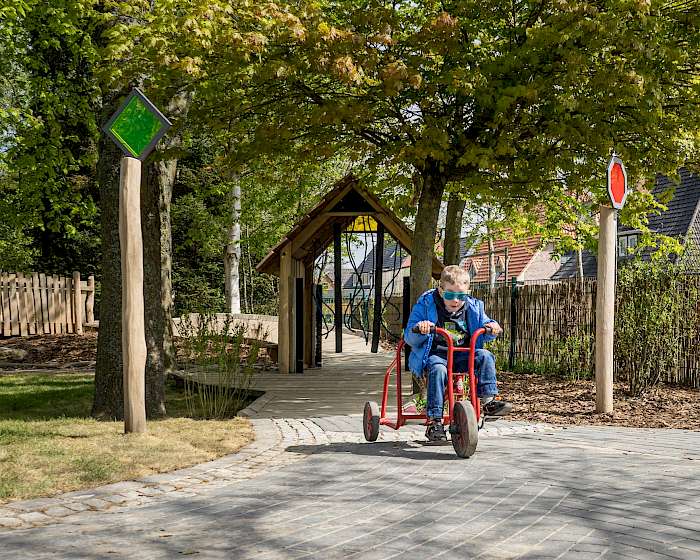 Kind auf Dreirad augf inklusivem Spielplatz