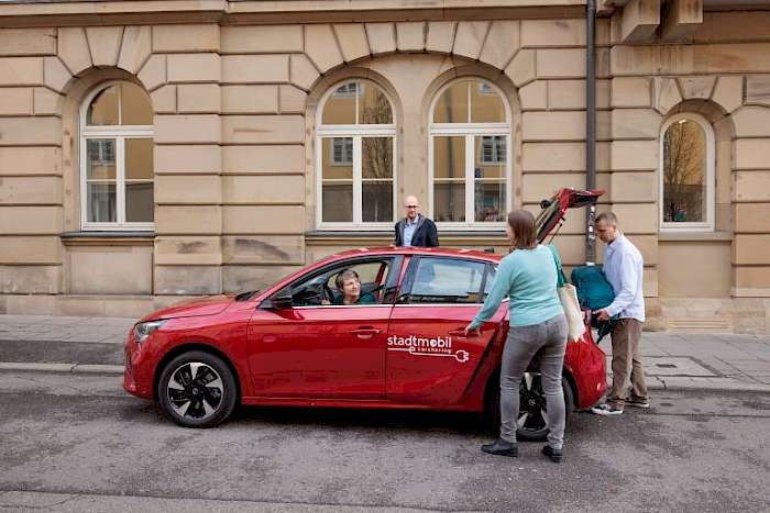 Drei Persone an einem Carsharing Fahrzeug